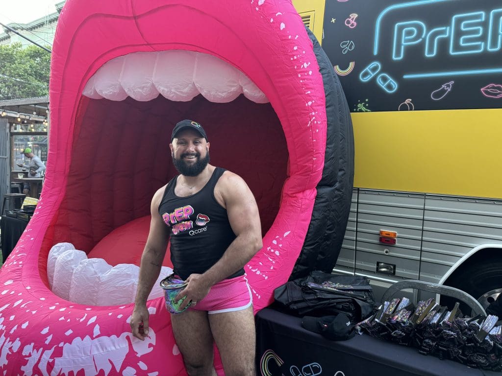 LGBTQ Man in front of giant inflatable lips and the Grindr Bus