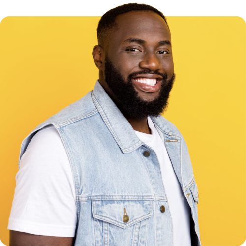 Smiling man in a denim vest against a yellow background, representing the ease and accessibility of at-home PrEP and Doxy-PEP testing with Q Care Plus.