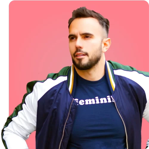 Hombre expresando confianza y orgullo Hombre con chaqueta deportiva y camiseta con la palabra "feminist" sobre un fondo rosa.